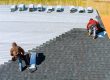 Two professional roofers are seen installing a roof on a house, with one roofer securing shingles and the other managing roofing materials during the roof installation process.